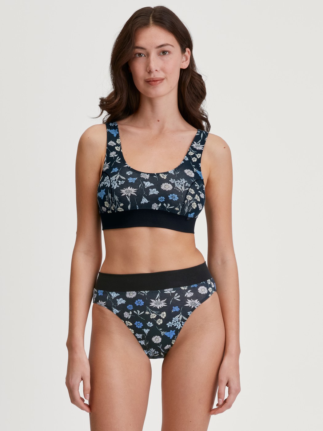 Damen-Model trägt Bustier mit Softbund aus Baumwolle in Schwarz, Floral aus Serie Elastic Trend von CALIDA, Outfit