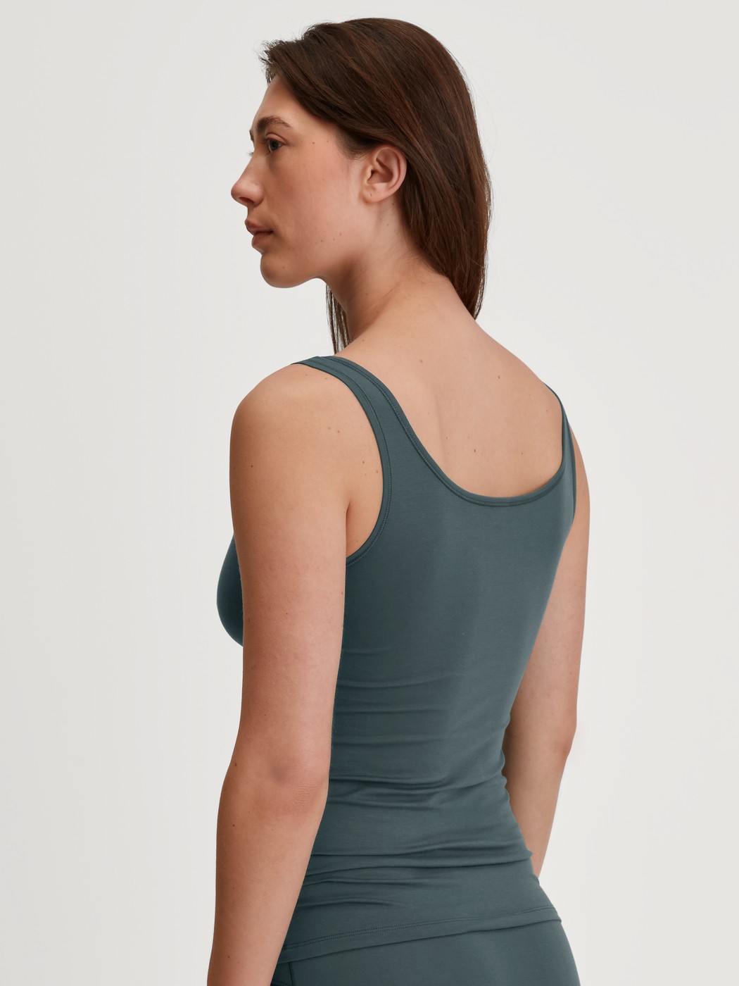 Women model is wearing Tank top made of Cotton in Green, Unicoloured from the Natural Comfort series by CALIDA, Back view