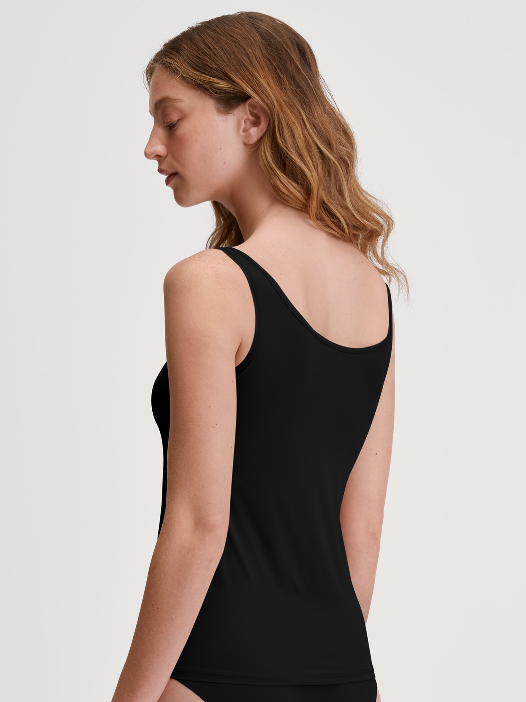 Damen-Model trägt Tank-Top aus Baumwolle in Schwarz, Einfarbig aus Serie Sleek Skin von CALIDA, Rückansicht