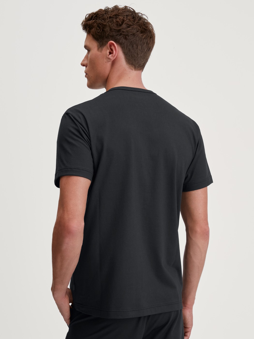 Herren-Model trägt Kurzarm-Shirt aus 100% Baumwolle in Schwarz, Einfarbig aus Serie RMX Sleep Leisure von CALIDA, Rückansicht