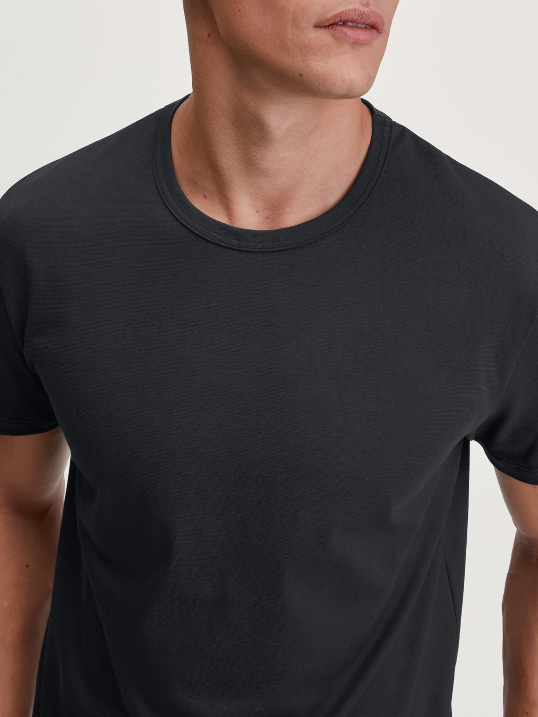 Herren-Model trägt Kurzarm-Shirt aus 100% Baumwolle in Schwarz, Einfarbig aus Serie RMX Sleep Leisure von CALIDA, Detail