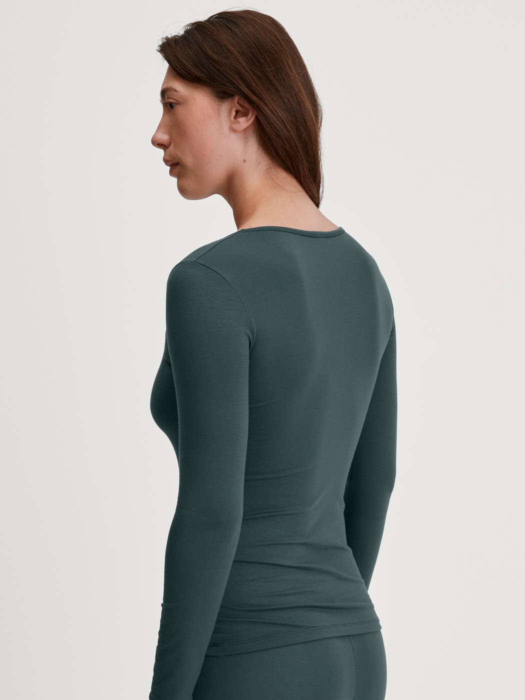 Damen-Model trägt Langarm-Shirt, Rundhals aus Baumwolle in Grün, Einfarbig aus Serie Natural Comfort von CALIDA, Rückansicht