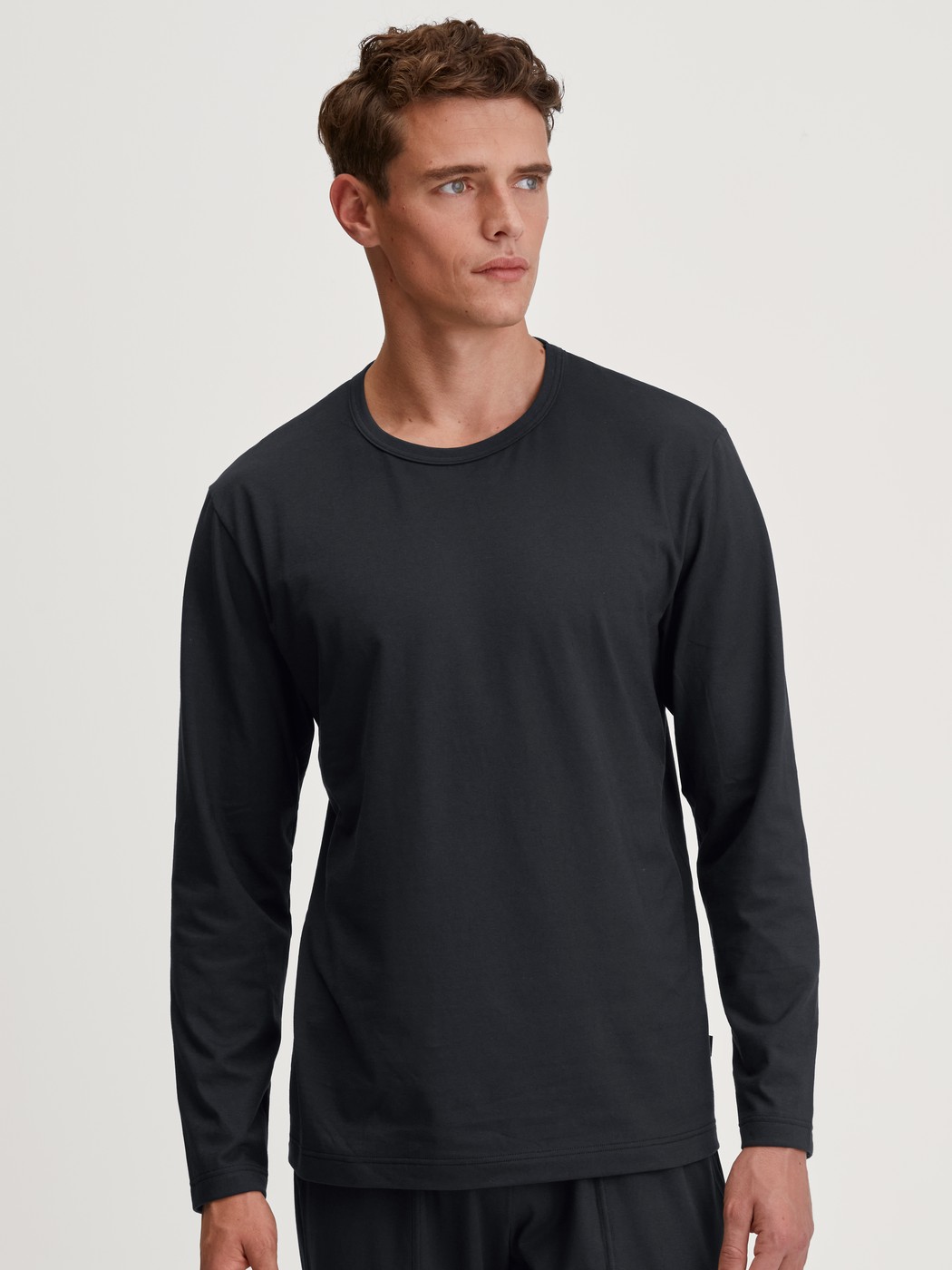 Herren-Model trägt Langarm-Shirt aus 100% Baumwolle in Schwarz, Einfarbig aus Serie RMX Sleep Leisure von CALIDA, Vorderansicht