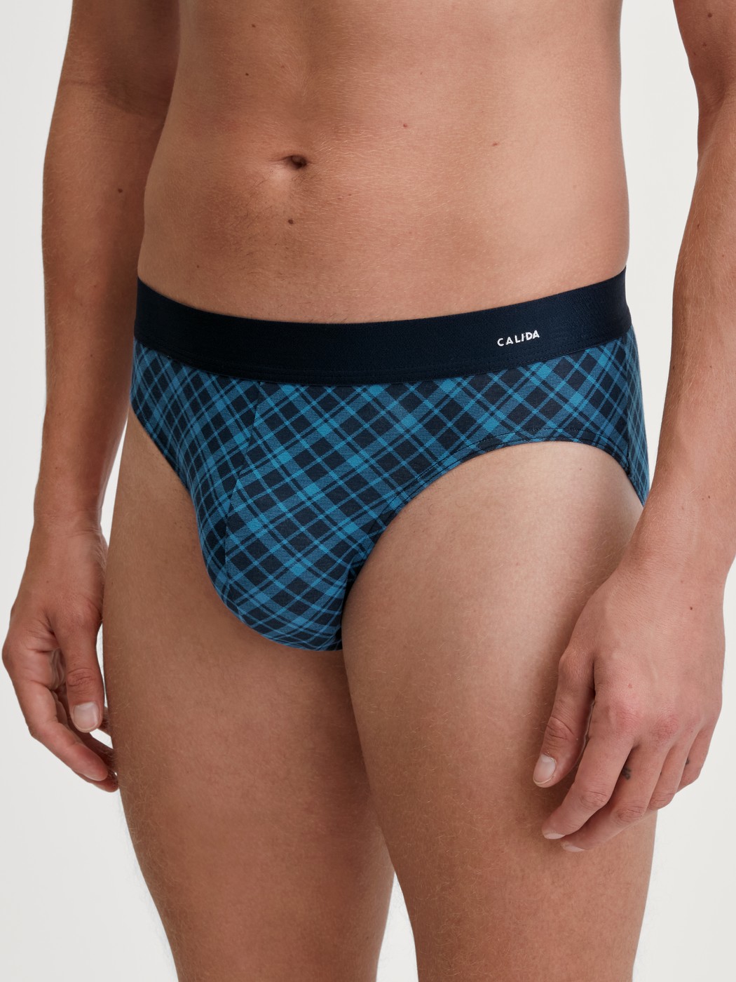 Herren-Model trägt Slip mit Softgummibund aus Baumwolle in Blau, Kariert aus Serie Cotton Code Design von CALIDA, Vorderansicht