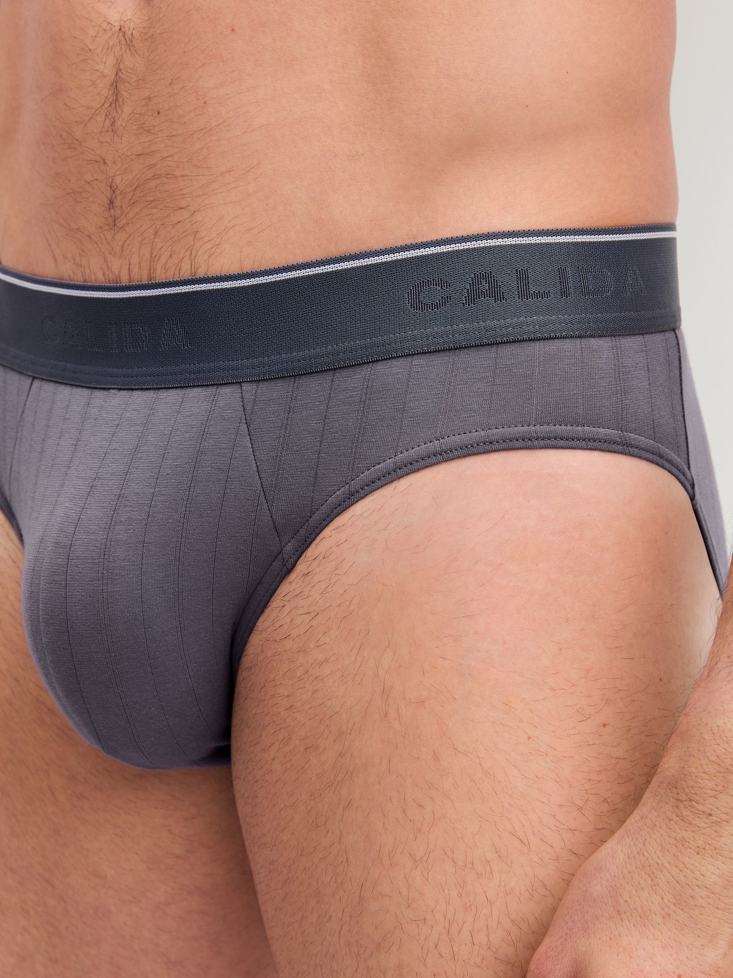 Herren-Model trägt Mini-Slip, Elastikbund aus Baumwolle in Grau, Einfarbig aus Serie Pure & Style von CALIDA, Detail