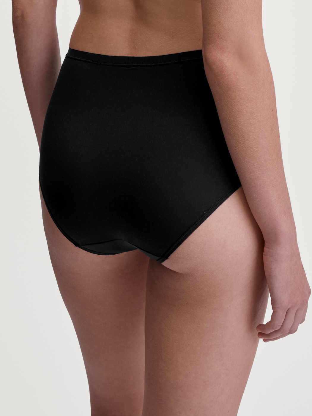 Damen-Model trägt Slip, high waist aus Polyamid in Schwarz, Einfarbig aus Serie Sleek Skin von CALIDA, Rückansicht