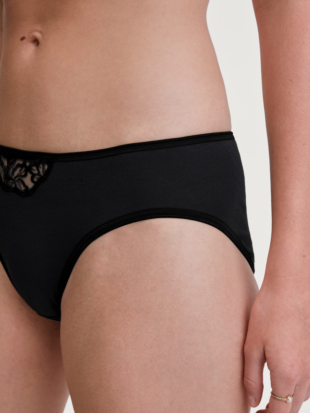 Damen-Model trägt Mini-Slip aus 100% Baumwolle in Schwarz, Spitze aus Serie Cotton Desire von CALIDA, Detail