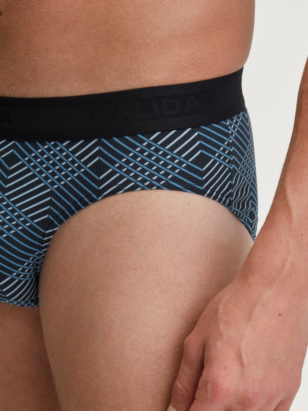 Herren-Model trägt Slip mit Softgummibund aus Baumwolle in Schwarz, Gemustert aus Serie Grafic Cotton von CALIDA, Detail
