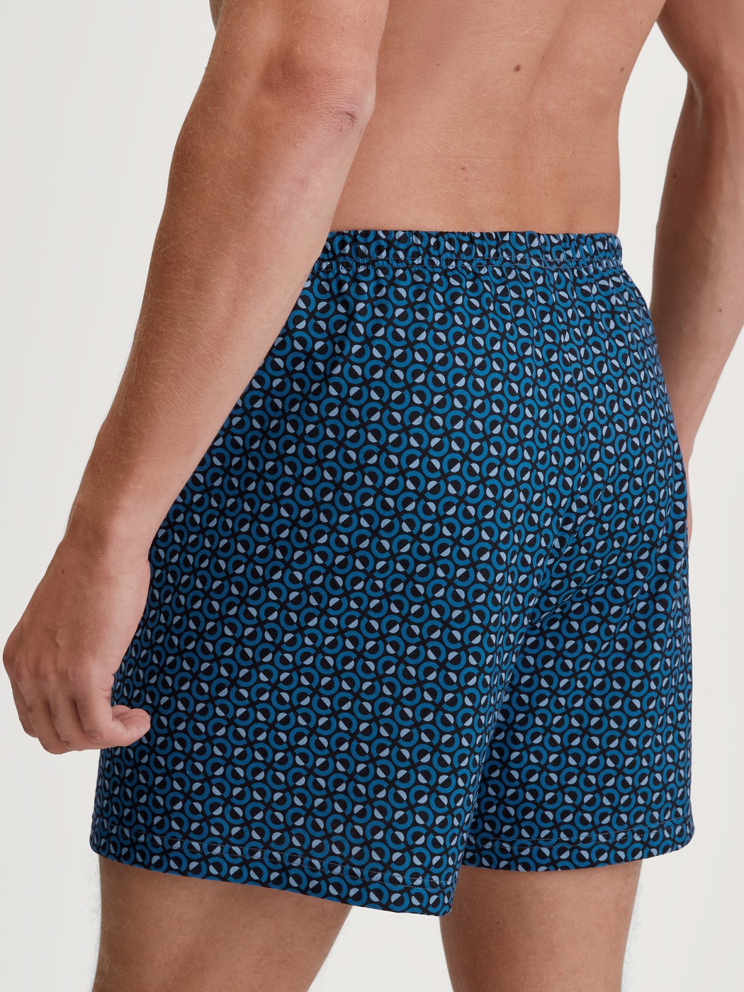 Herren-Model trägt Jersey-Boxershorts ohne Eingriff aus 100% Baumwolle in Blau, Gemustert aus Serie Prints von CALIDA, Rückansicht