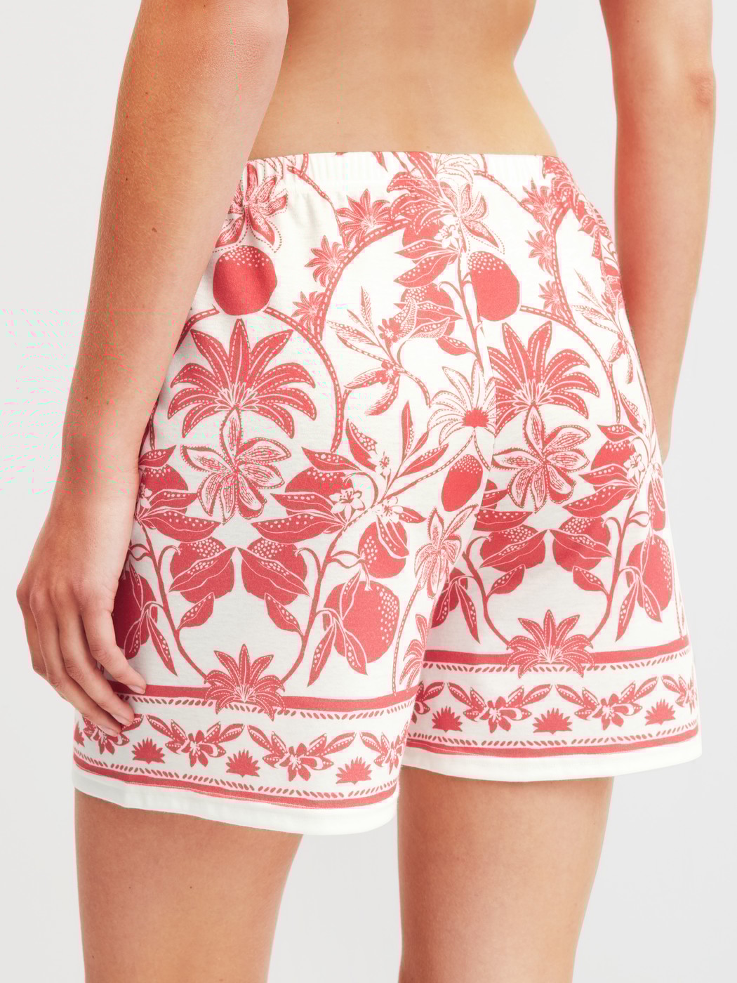 Women model is wearing Pyjama shorts made of 100% Cotton in Orange, Floral from the Favourites Beach series by CALIDA, Back view