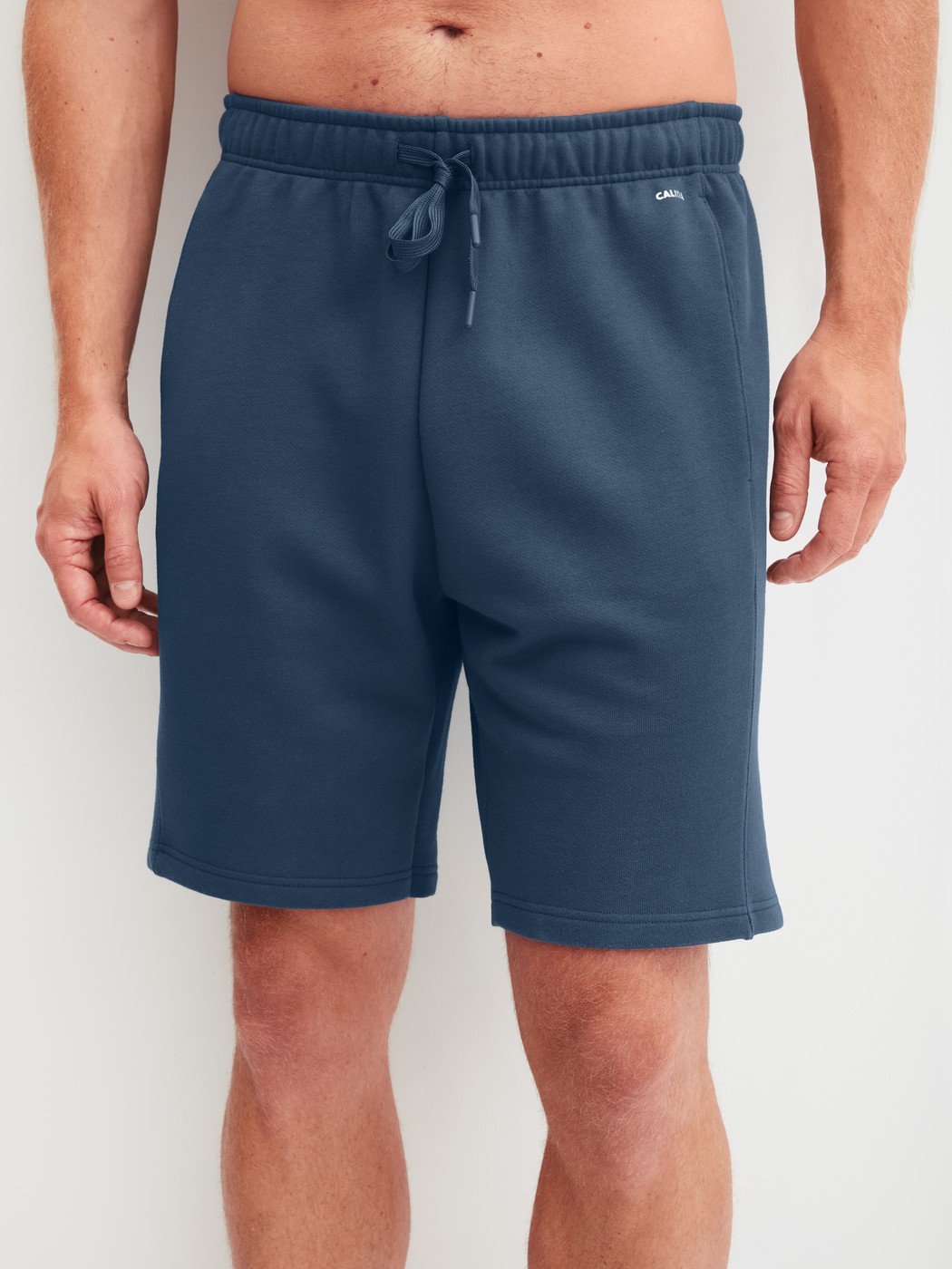 Men model is wearing Bermudas with side pockets made of Cotton in Blue, Unicoloured from the RMX Lounge Journey series by CALIDA, Front view