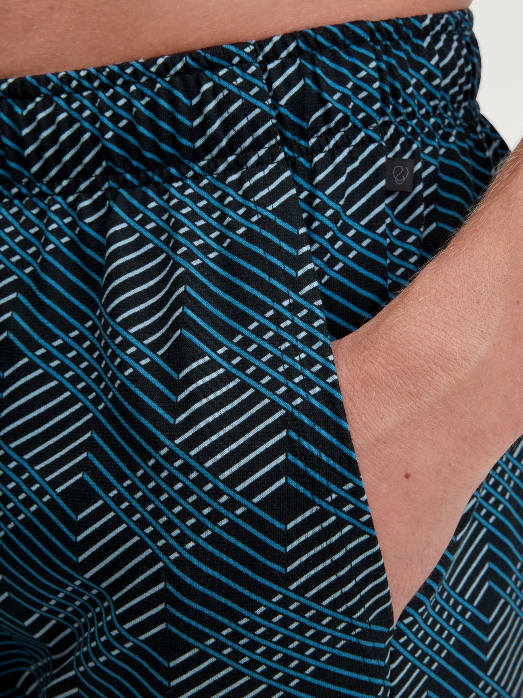 Herren-Model trägt Bermudas aus 100% Baumwolle in Schwarz, Gemustert aus Serie RMX Sleep Leisure von CALIDA, Detail