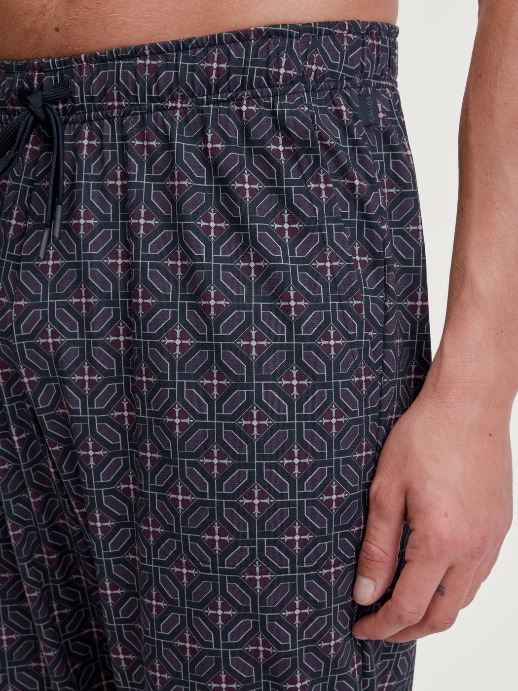 Herren-Model trägt Pyjamahose mit Seitentaschen aus 100% Baumwolle in Braun, Gemustert aus Serie RMX Sleep Holiday von CALIDA, Detail