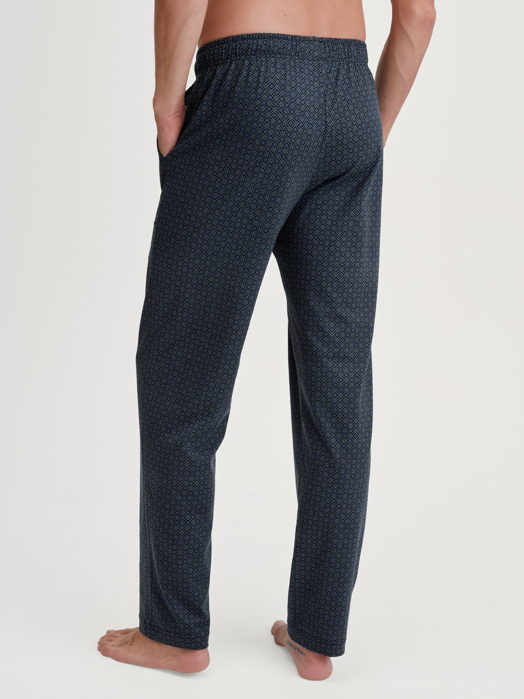 Herren-Model trägt Pyjamahose mit Seitentaschen aus 100% Baumwolle in Blau, Gemustert aus Serie RMX Sleep Weekend von CALIDA, Rückansicht