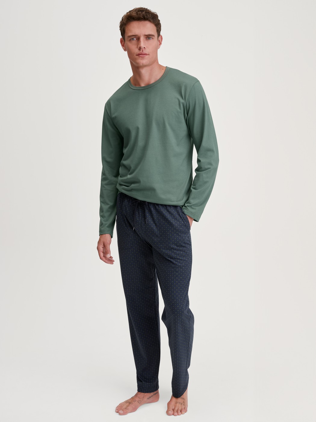 Herren-Model trägt Pyjamahose mit Seitentaschen aus 100% Baumwolle in Blau, Gemustert aus Serie RMX Sleep Weekend von CALIDA, Outfit