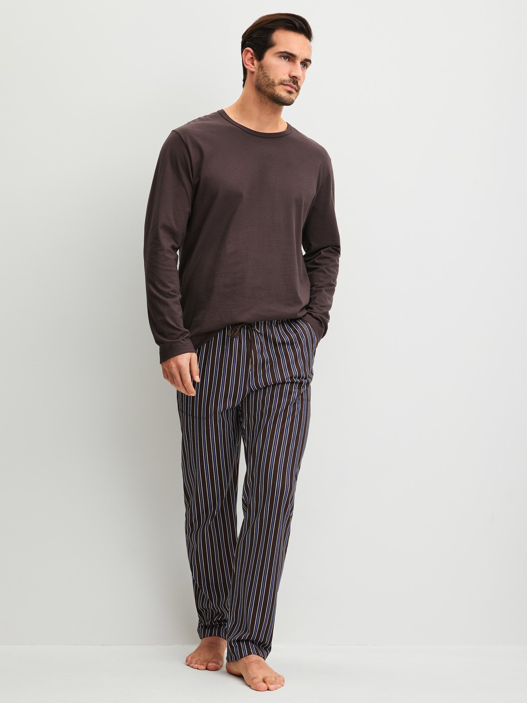 Men model is wearing Pyjama Bottoms with Side Pockets made of 100% Cotton in Brown, Striped from the RMX Sleep Weekend series by CALIDA, Outfit