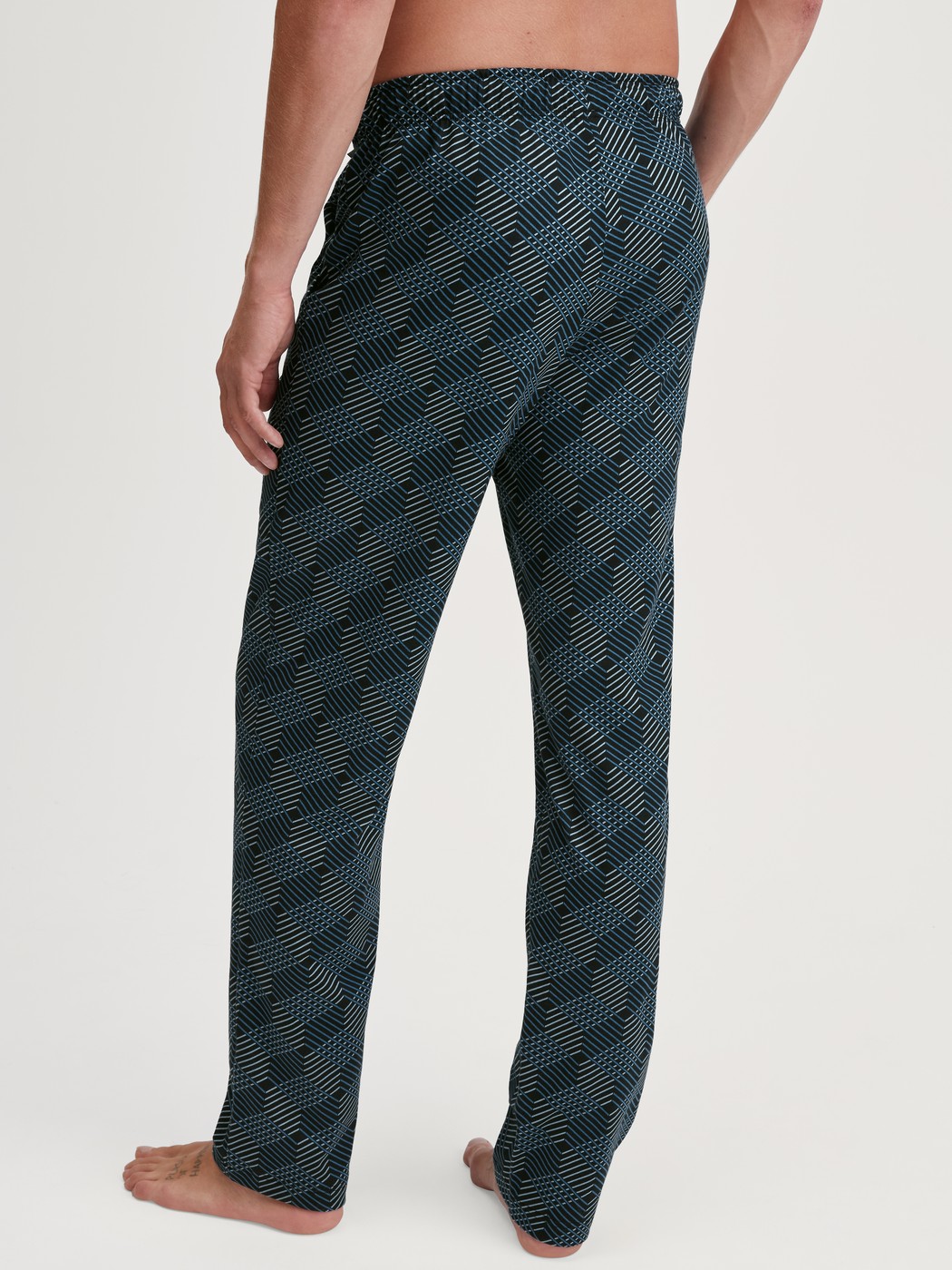 Herren-Model trägt Pyjamahose mit Seitentaschen aus 100% Baumwolle in Schwarz, Gemustert aus Serie RMX Sleep Leisure von CALIDA, Rückansicht