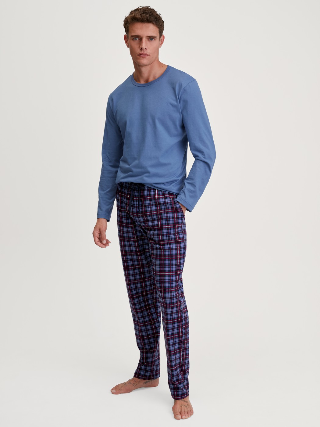 Herren-Model trägt Pyjamahose mit Seitentaschen aus 100% Baumwolle in Blau, Gemustert aus Serie Family & Friends von CALIDA, Outfit