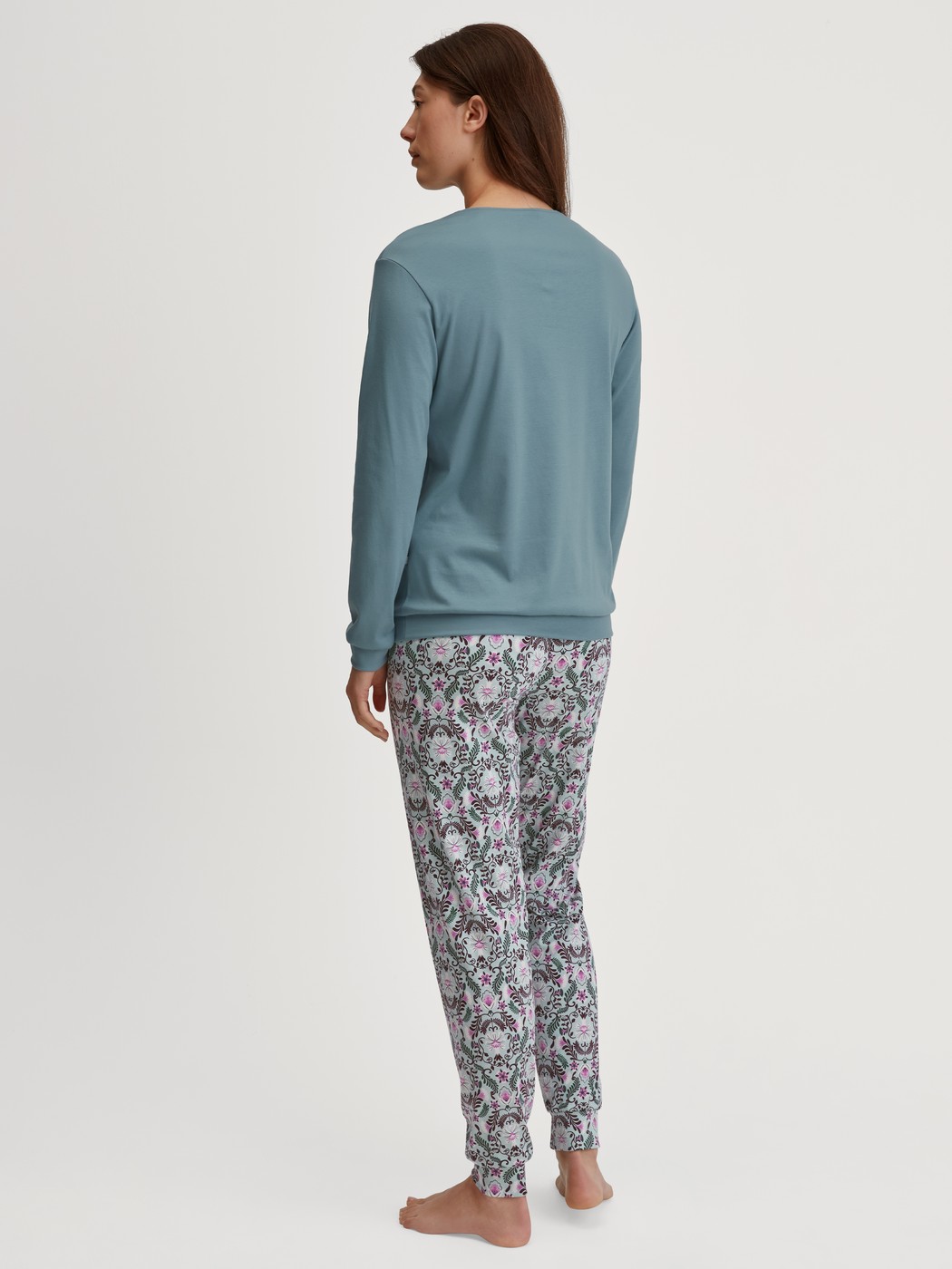 Damen-Model trägt Bündchen-Pyjama aus 100% Baumwolle in Blau, Gemustert aus Serie Autumn Dreams von CALIDA, Rückansicht