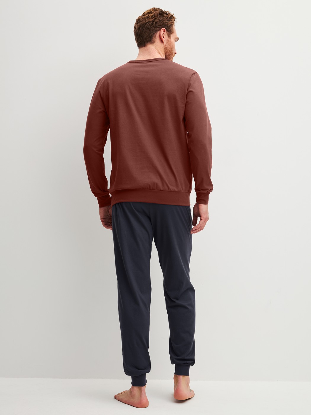 Herren-Model trägt Bündchen-Pyjama aus 100% Baumwolle in Rot, Einfarbig aus Serie Relax Essentials von CALIDA, Rückansicht