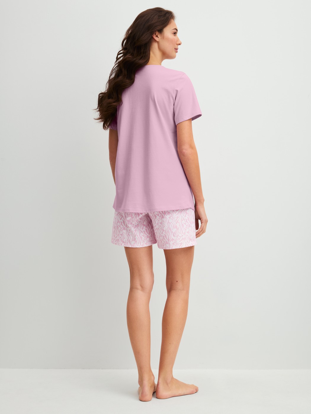Damen-Model trägt Kurz-Pyjama aus 100% Baumwolle in Violett, Gemustert aus Serie Blooming Nights von CALIDA, Rückansicht
