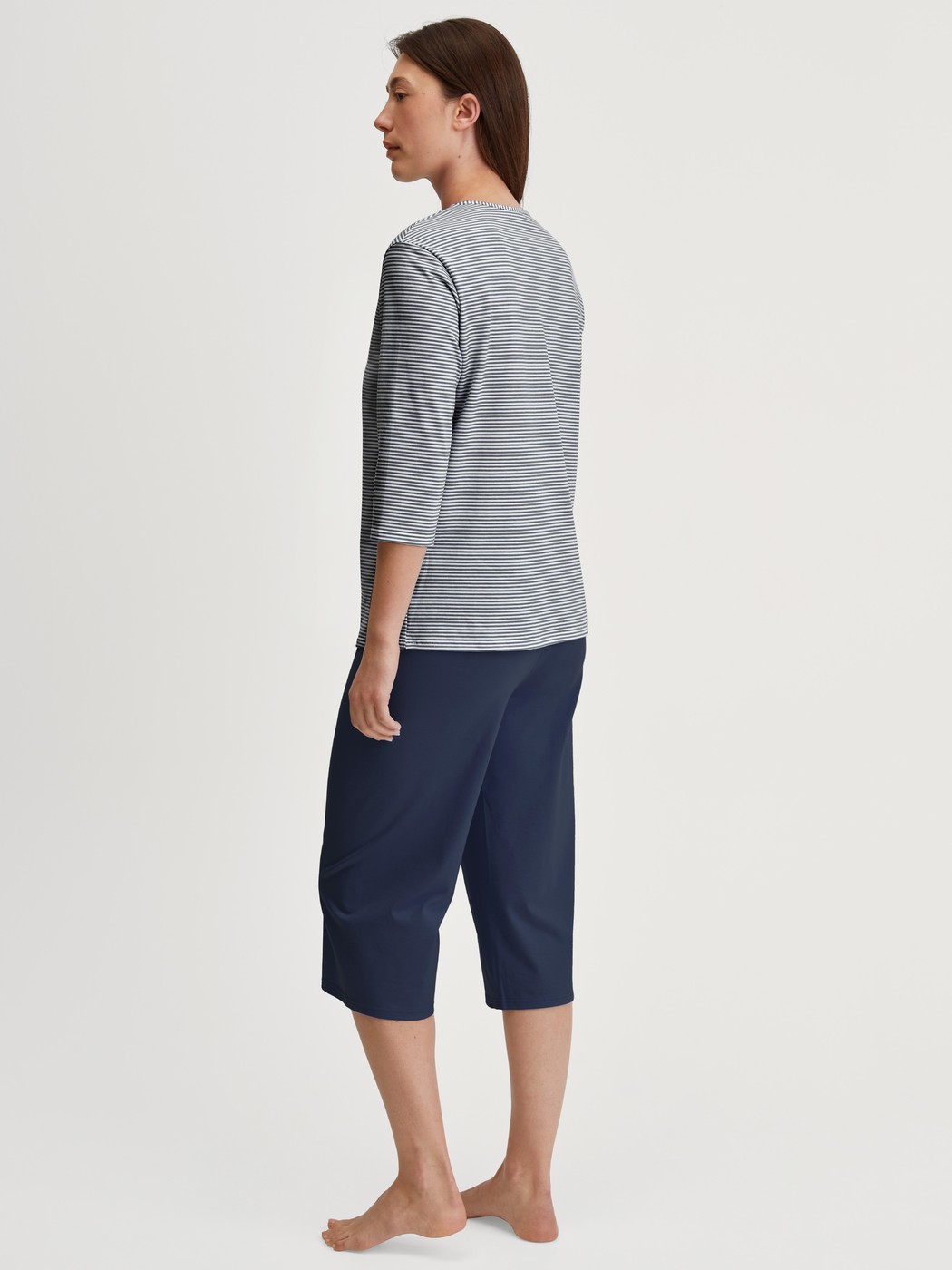 Women model is wearing Capri Pyjama made of 100% Cotton in Blue, Patterned from the Cotton Special series by CALIDA, Back view
