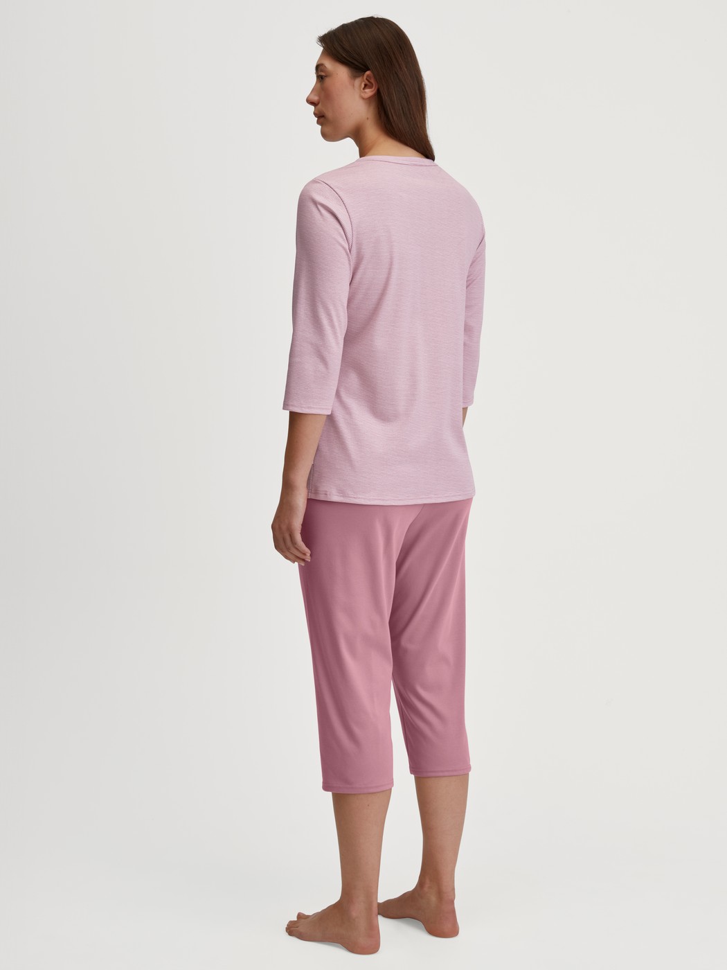 Damen-Model trägt Capri-Pyjama aus 100% Baumwolle in Rosa, Gestreift aus Serie Striped Dreams von CALIDA, Rückansicht