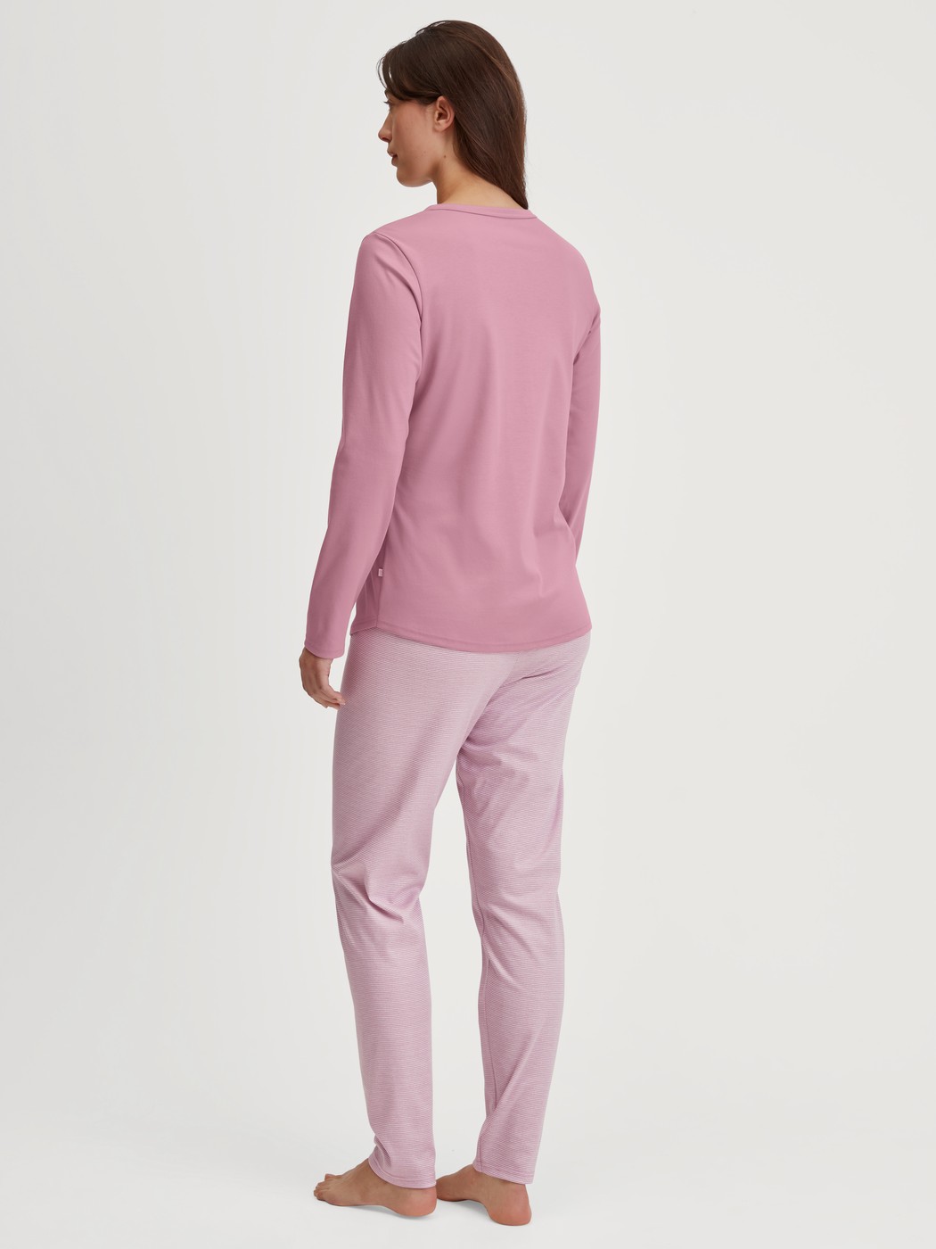 Damen-Model trägt Pyjama, lang aus 100% Baumwolle in Rosa, Gestreift aus Serie Striped Dreams von CALIDA, Rückansicht