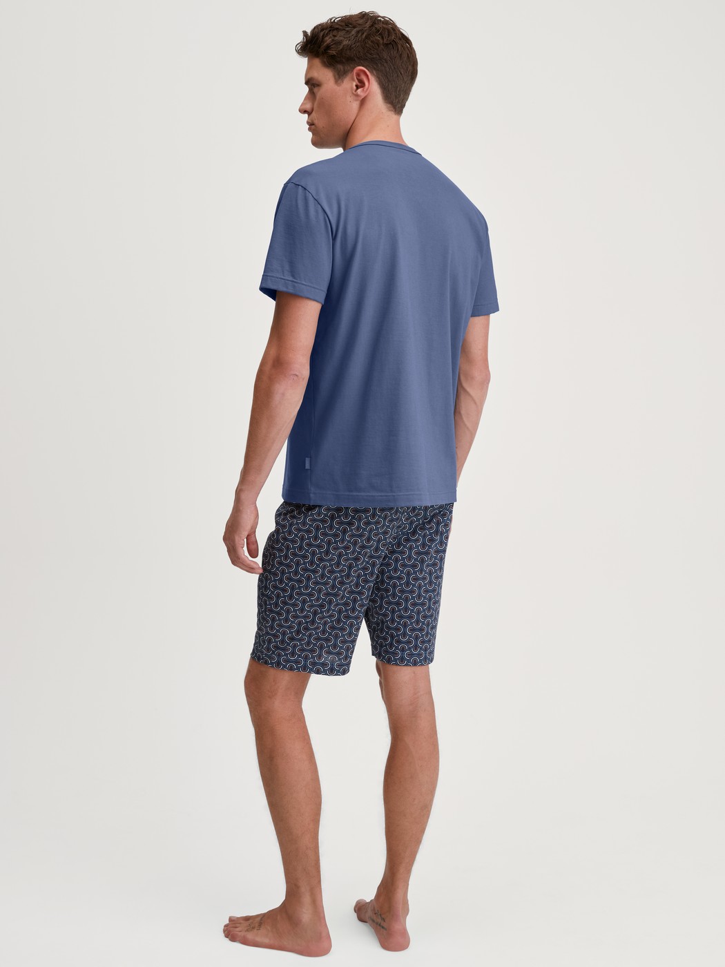 Herren-Model trägt Kurz-Pyjama aus 100% Baumwolle in Blau, Gemustert aus Serie Relax Imprint 1 von CALIDA, Rückansicht