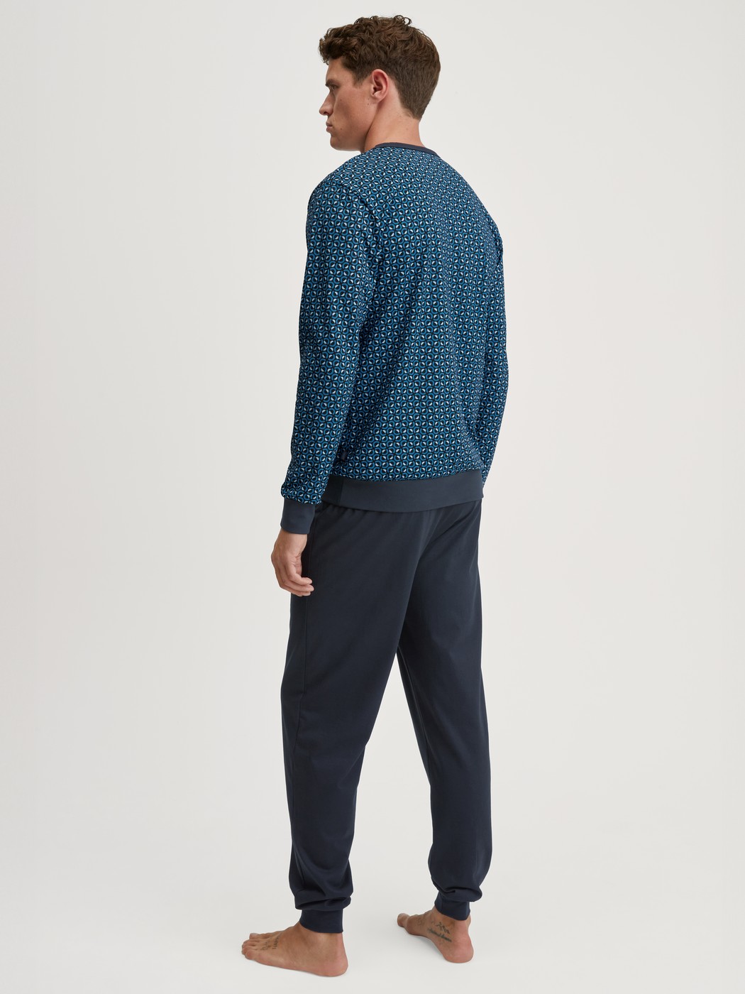 Herren-Model trägt Bündchen-Pyjama aus 100% Baumwolle in Blau, Gemustert aus Serie Relax Imprint 2 von CALIDA, Rückansicht