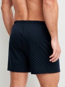 Men model is wearing Boxer shorts made of 100% Cotton in Blue, Patterned from the Prints series by CALIDA, Back view