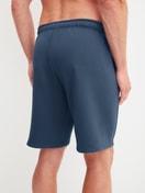 Men model is wearing Bermudas with side pockets made of Cotton in Blue, Unicoloured from the RMX Lounge Journey series by CALIDA, Back view