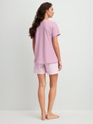 Damen-Model trägt Kurz-Pyjama aus 100% Baumwolle in Violett, Gemustert aus Serie Blooming Nights von CALIDA, Rückansicht