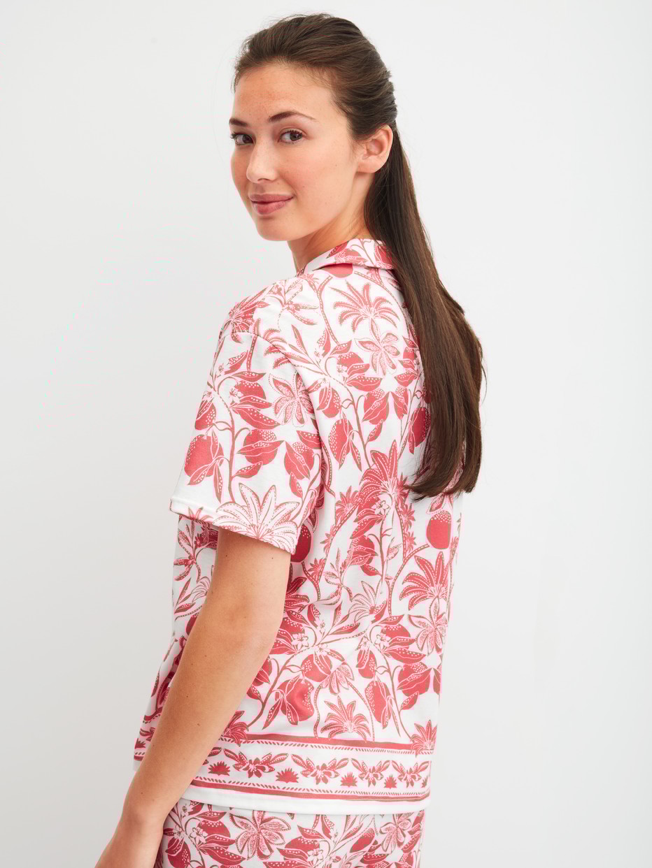 Damen-Model trägt Kurzarm-Shirt mit Knöpfen aus 100% Baumwolle in Orange, Floral aus Serie Favourites Beach von CALIDA, Rückansicht