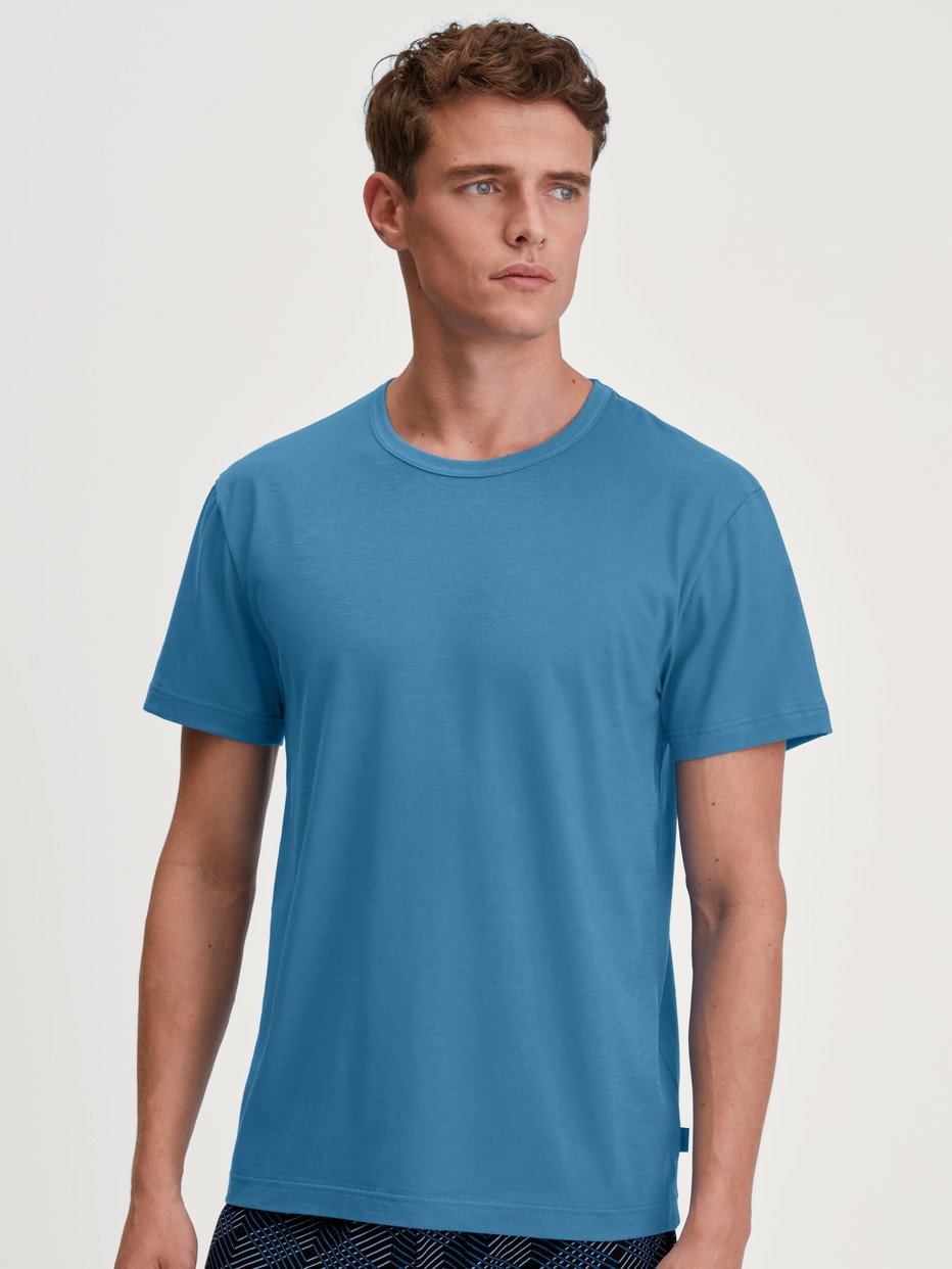 Herren-Model trägt Kurzarm-Shirt aus 100% Baumwolle in Blau, Einfarbig aus Serie RMX Sleep Leisure von CALIDA, Vorderansicht
