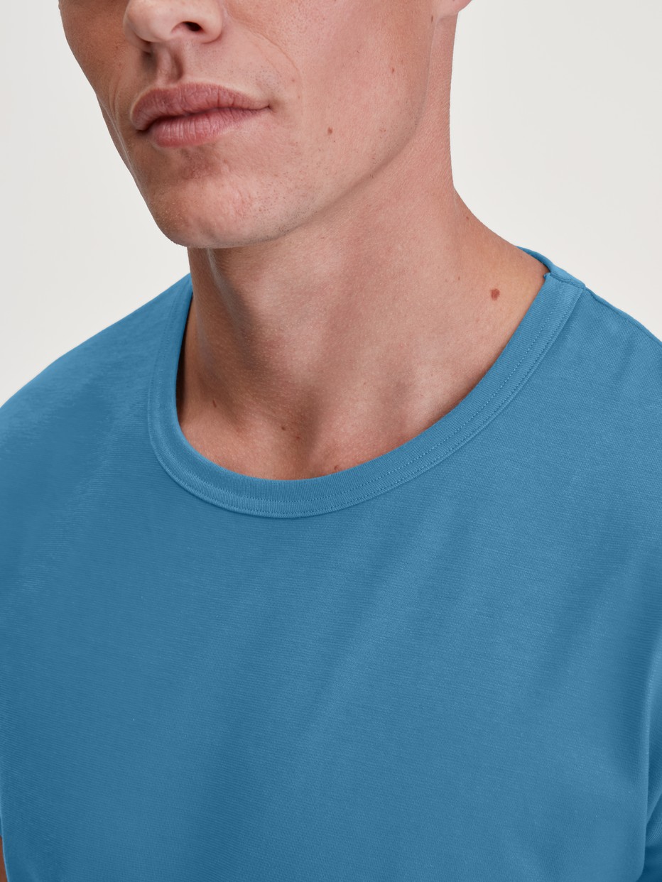 Herren-Model trägt Kurzarm-Shirt aus 100% Baumwolle in Blau, Einfarbig aus Serie RMX Sleep Leisure von CALIDA, Detail