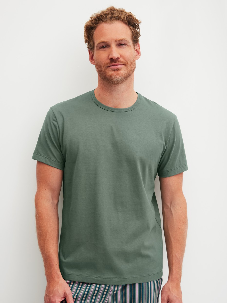 Herren-Model trägt Kurzarm-Shirt aus 100% Baumwolle in Grün, Einfarbig aus Serie RMX Sleep Leisure von CALIDA, Vorderansicht