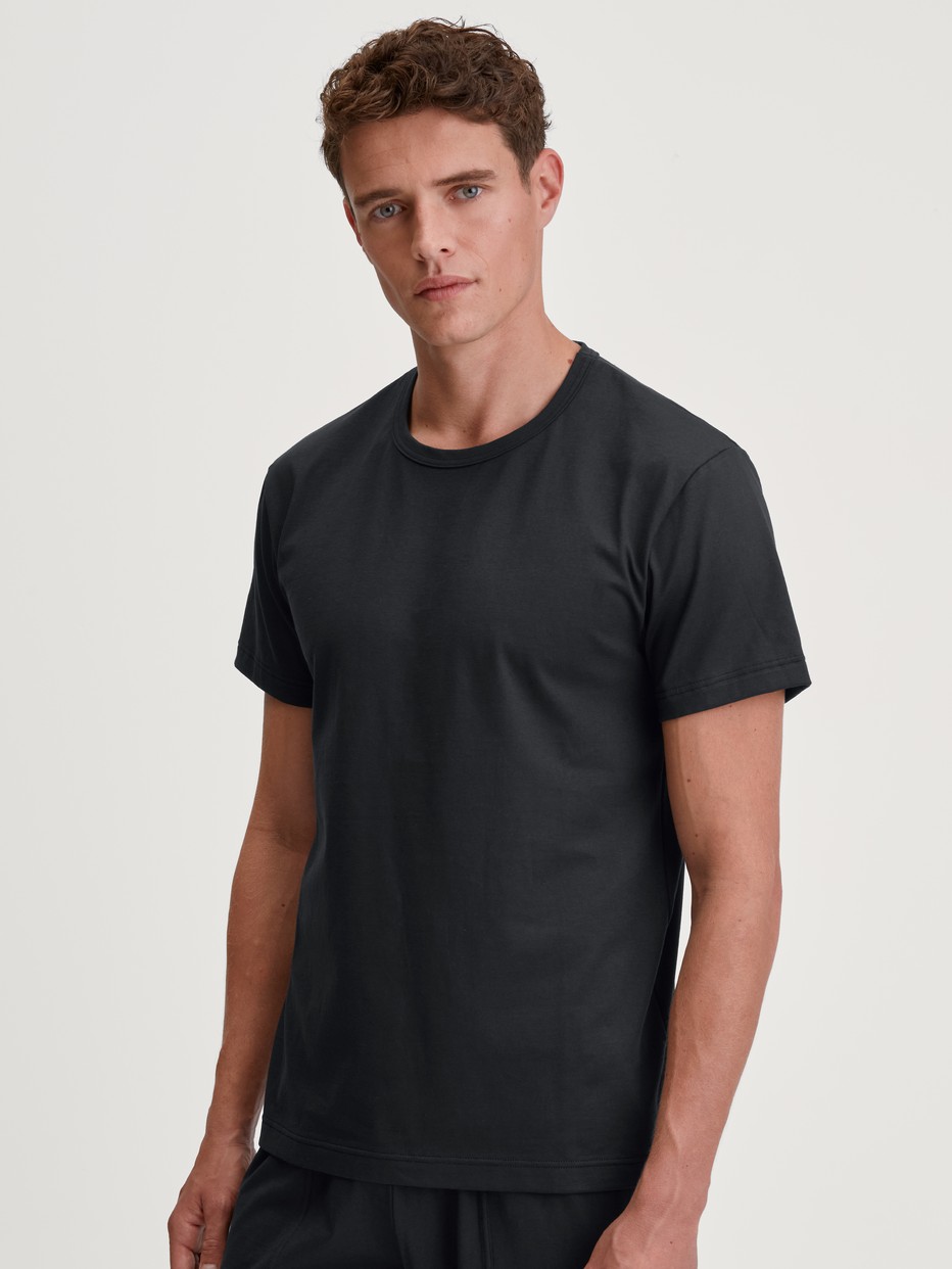 Men model is wearing Short-sleeved shirt made of 100% Cotton in Black, Unicoloured from the RMX Sleep Leisure series by CALIDA, Front view