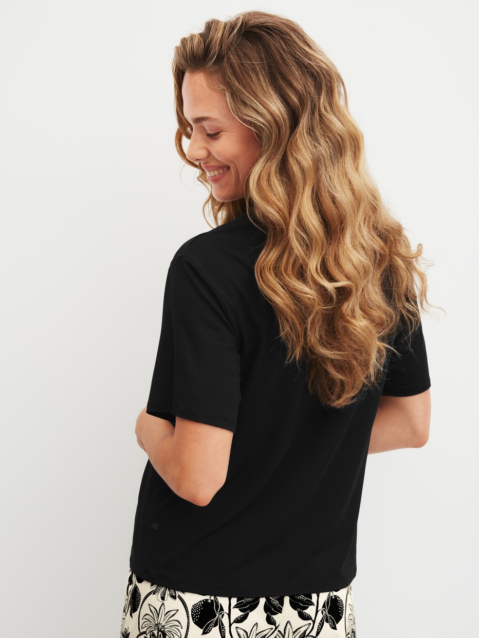 Women model is wearing Shirt short sleeve made of Modal in Black, Unicoloured from the Favourites Layering series by CALIDA, Back view