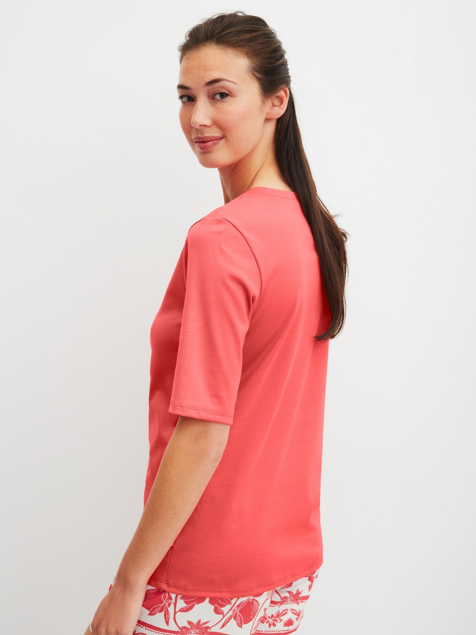 Women model is wearing Short-sleeved shirt made of 100% Cotton in Orange, Unicoloured from the Favourites Beach series by CALIDA, Back view