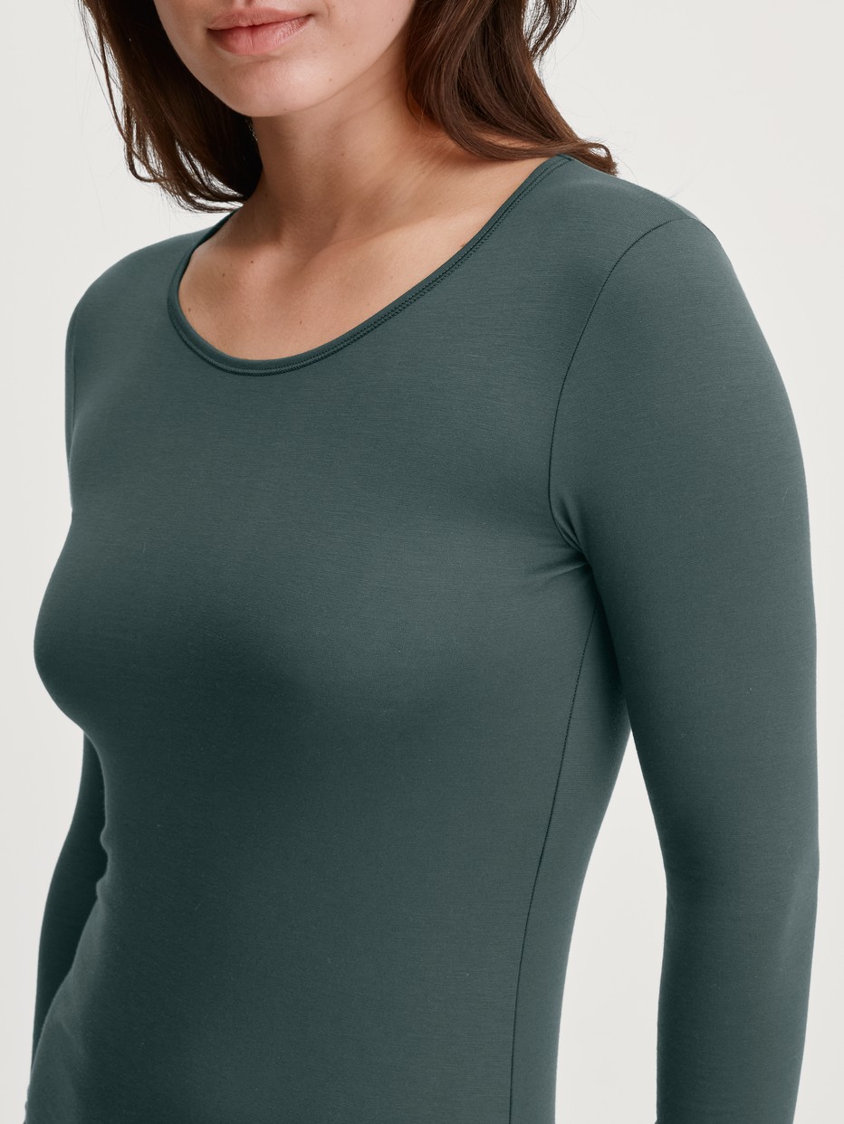 Damen-Model trägt Langarm-Shirt, Rundhals aus Baumwolle in Grün, Einfarbig aus Serie Natural Comfort von CALIDA, Detail