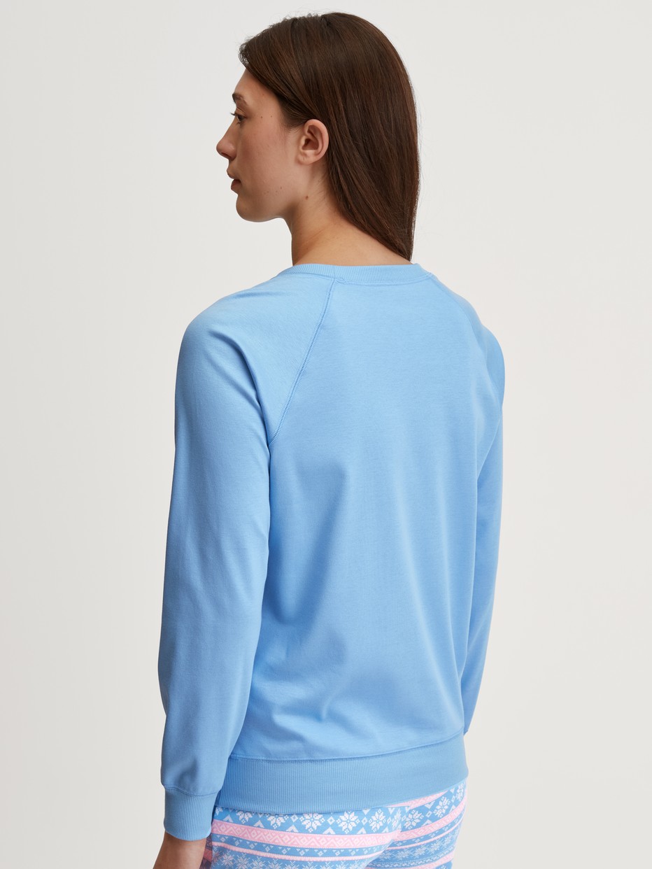Women model is wearing Shirt long sleeve made of 100% Cotton in Blue, Unicoloured from the Ski Resort series by CALIDA, Back view