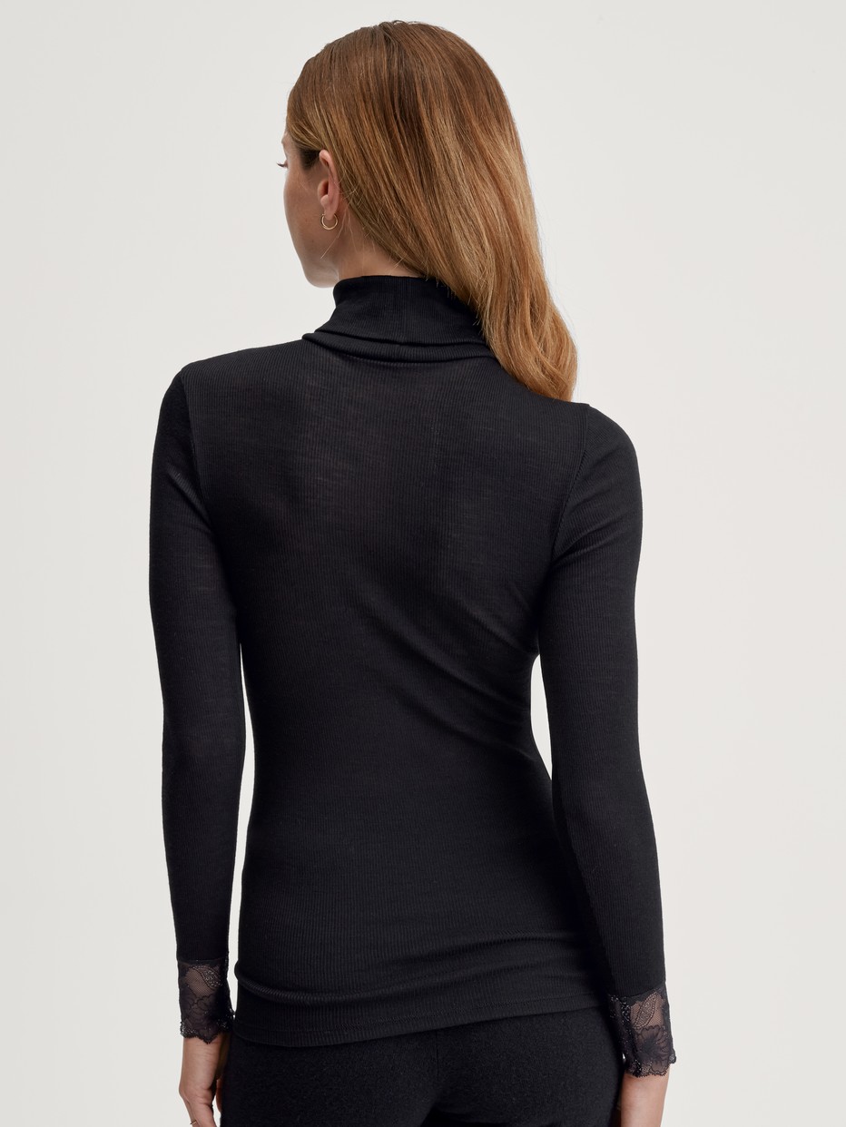 Damen-Model trägt Langarm-Shirt mit Rollkragen aus Wolle-Seide aus Spitze in Schwarz, Spitze aus Serie Silky Wool Glam von CALIDA, Rückansicht