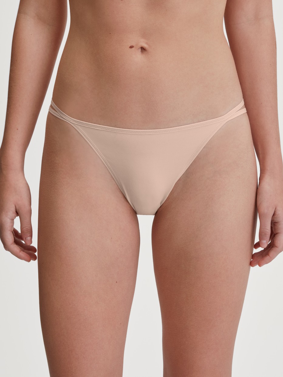 Damen-Model trägt Tanga-Slip, low cut aus Polyamid in Rosa, Einfarbig aus Serie Sleek Skin von CALIDA, Vorderansicht