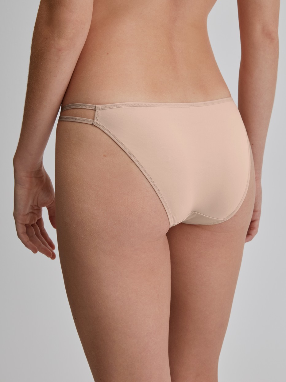 Damen-Model trägt Tanga-Slip, low cut aus Polyamid in Rosa, Einfarbig aus Serie Sleek Skin von CALIDA, Rückansicht