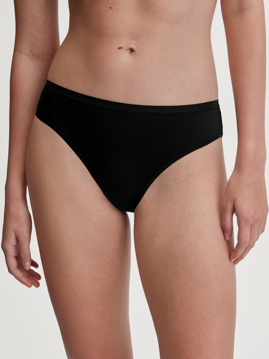 Damen-Model trägt Slip, regular cut aus Polyamid in Schwarz, Einfarbig aus Serie Sleek Skin von CALIDA, Vorderansicht