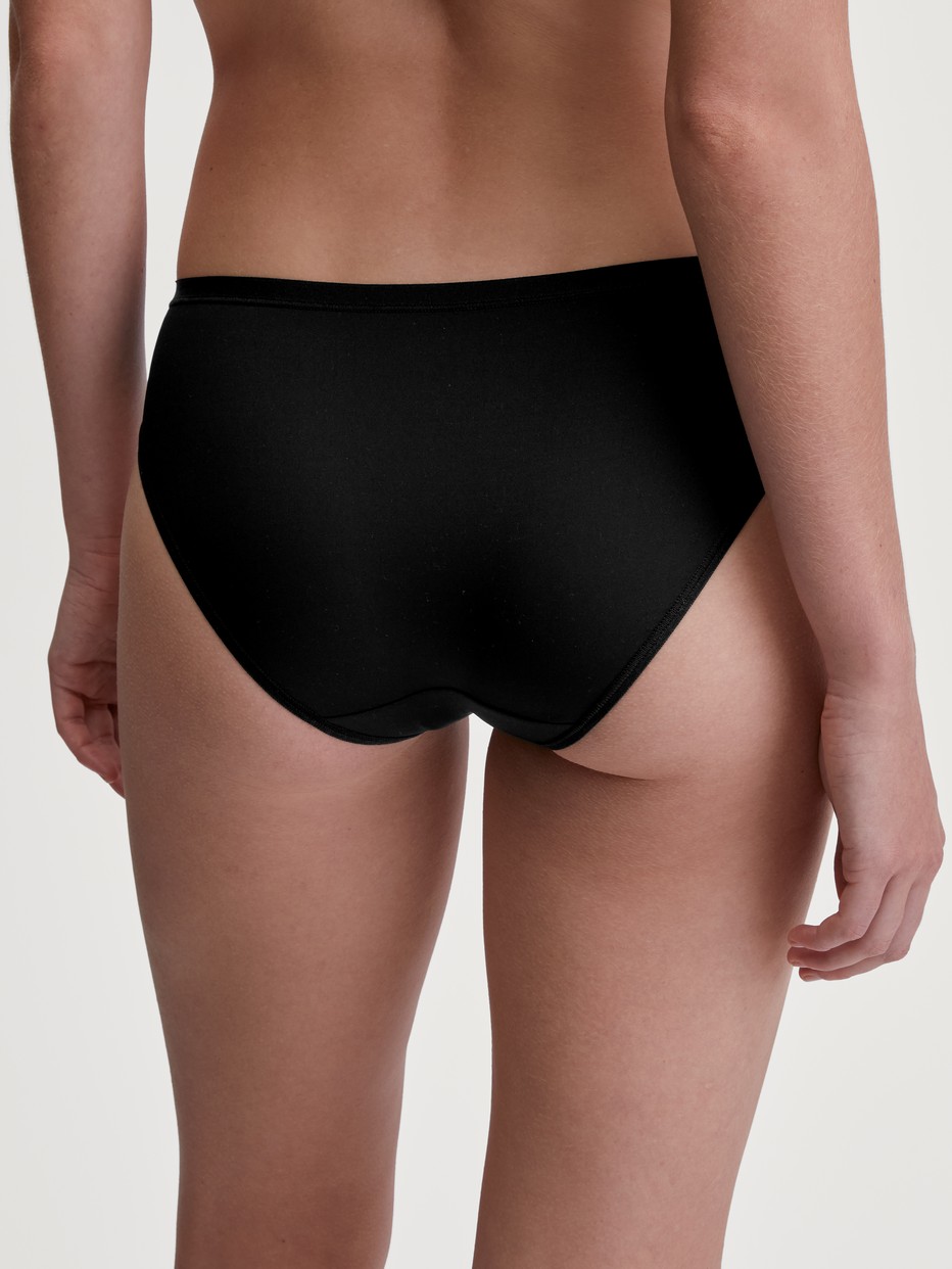 Damen-Model trägt Slip, regular cut aus Polyamid in Schwarz, Einfarbig aus Serie Sleek Skin von CALIDA, Rückansicht