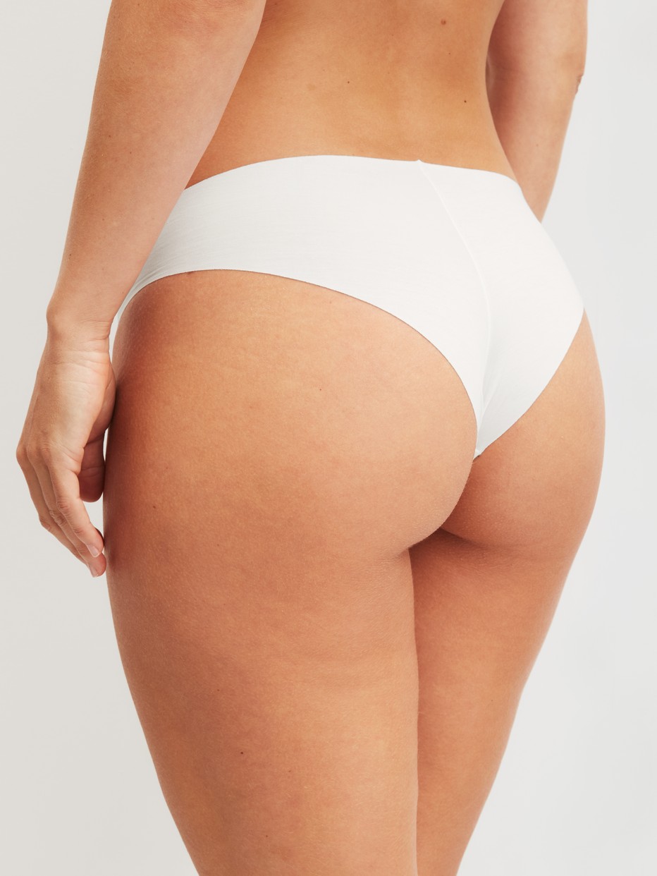 Women model is wearing Seamless Brazilian Brief made of Modal in White, Unicoloured from the Natural Skin series by CALIDA, Back view