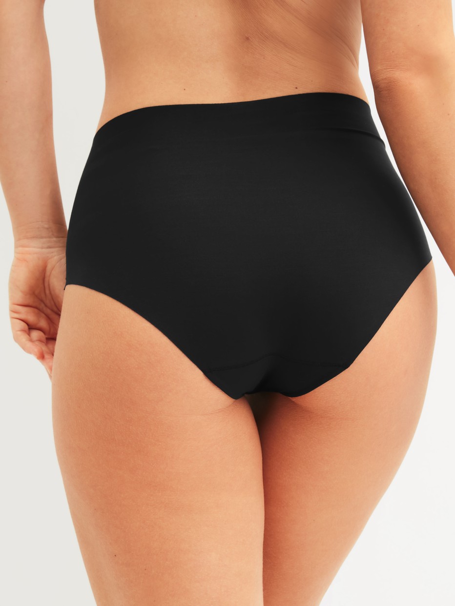Damen-Model trägt Seamless High-Waist Slip aus Modal in Schwarz, Einfarbig aus Serie Natural Skin von CALIDA, Rückansicht