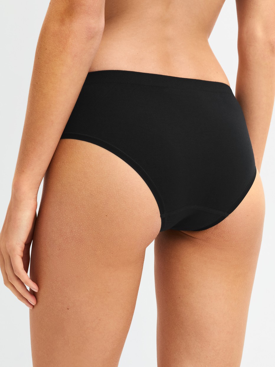 La modella / Il modello Donna indossa Slip in Modal di colore Nero, Tinta unita, della serie Seamless Natural di CALIDA, Vista posteriore